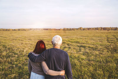 Rear view of couple on field against sky
