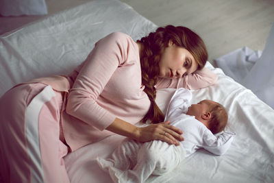 Mom with a small newborn daughter lying on the bed in the bedroom