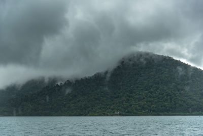 Scenic view of mountain by sea against sky