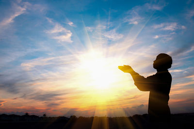 Side view of silhouette man standing against cloudy sky during sunset