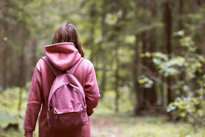 Rear view of woman standing amidst trees in forest