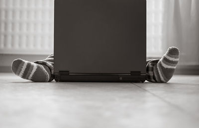 Low section of person sitting by laptop