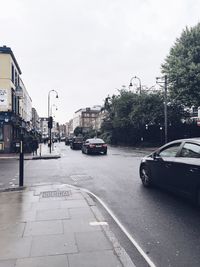 Cars on city street against sky