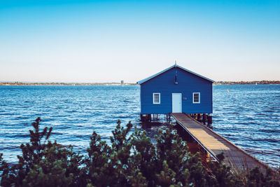 House by sea against clear blue sky