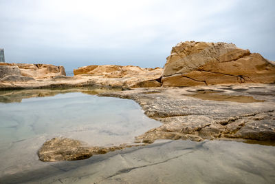 Rock formations by sea against sky