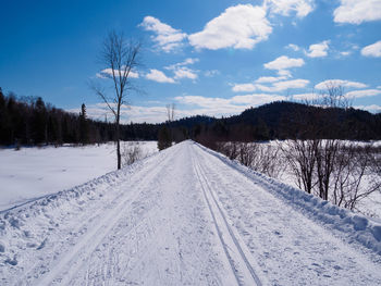 Ski tracks on snow covered landscape against sky