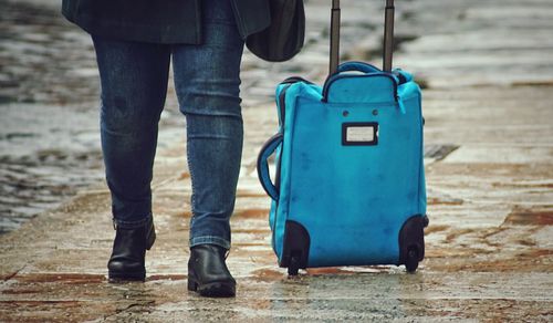 Low section of woman walking with luggage on footpath