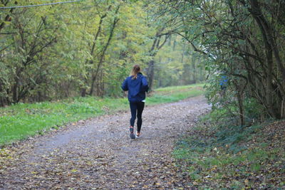 Full length and rear view of woman running on road