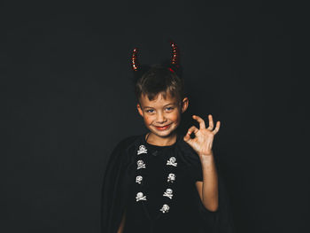 Portrait of boy standing against black background