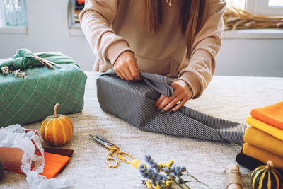 Midsection of woman wrapping gift with textile