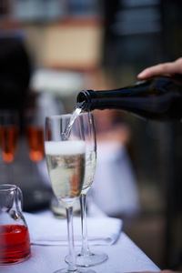 Close-up of human hand pouring wine in wineglass on table