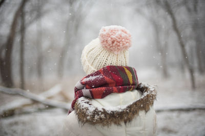 Rear view of person in forest during snowfall