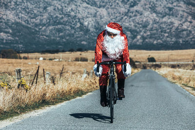 Rear view of woman riding bicycle on road