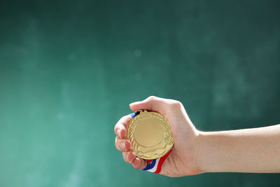 Close-up of hand holding ice cream against wall