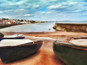 Boats in sea against cloudy sky