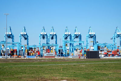 Cranes at commercial dock against clear sky