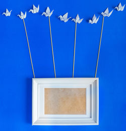 Picture frame and origami art work against blue background