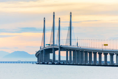 Bridge over sea against sky during sunset