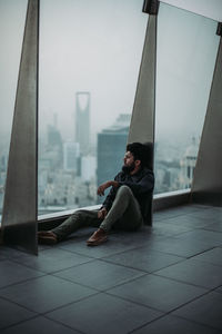 Side view of young man sitting on floor