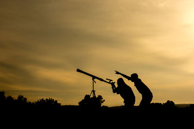 Silhouette man standing on field against sky during sunset