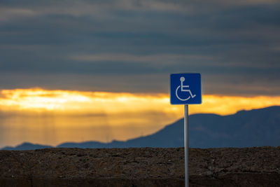 Handicapped car parking sign against sunset
