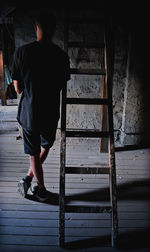 Rear view of man standing on hardwood floor