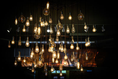 Low angle view of illuminated pendant lights hanging from ceiling