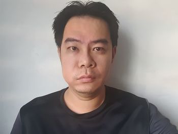 Portrait of young man standing against wall