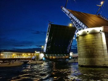 Illuminated bridge over sea against sky at night