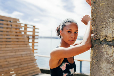 Portrait of young woman standing against wall