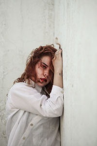 Portrait of young woman standing against wall