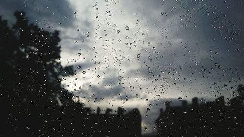 Raindrops on window against sky