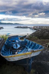 Scenic view of sea with damaged boat at beach against sky