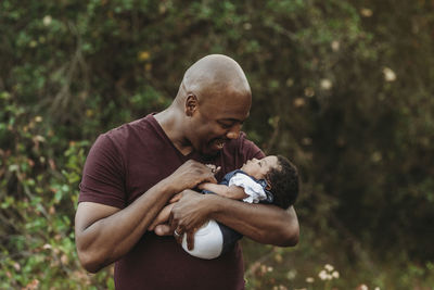 Close up happy father holding and smiling at newborn baby outside