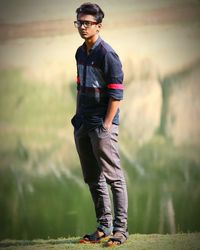 Portrait of young man wearing sunglasses standing on field