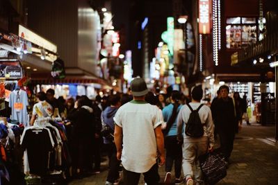 Rear view of people walking on street at night