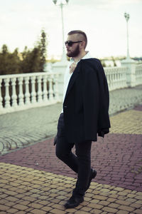 Full length of young man standing on footpath