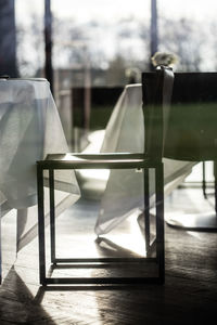 Empty chairs and table against window