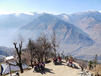 High angle view of children sitting on bench by trees against mountains