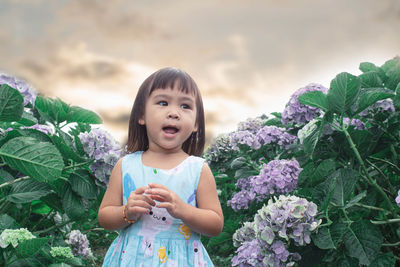 Cute girl with flowers against plants