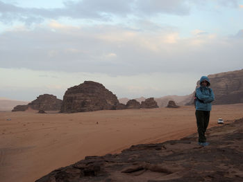 Rear view of man standing on rock against sky