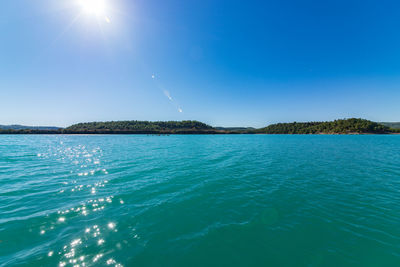 Scenic view of sea against blue sky on sunny day