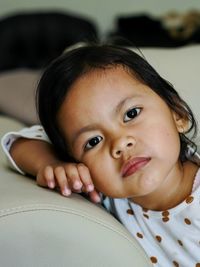 Close-up portrait of young little girl sitting on the sofa