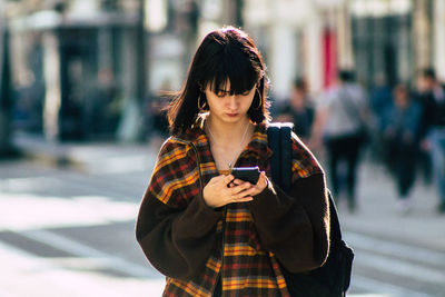 Woman looking at camera while standing on mobile phone