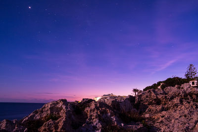 View at dawn of purple sky with stars and rocky pier in mallorca. 