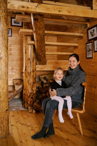 Full length of young woman sitting on hardwood floor