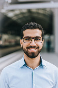 Portrait of young man standing at railroad station platform