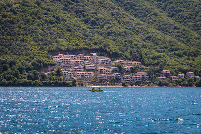 Scenic view of sea by buildings against mountain