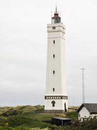 Low angle view of lighthouse by building against sky