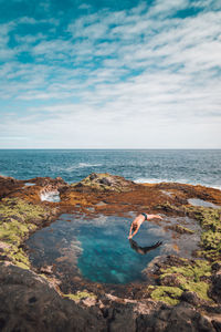 Shirtless man diving in sea against sky